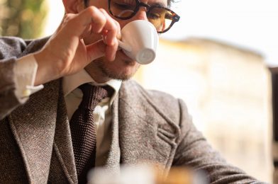 Brown Donegal tweed suit with flecked weave, cream shirt and brown knit tie, worn by a model sipping espresso