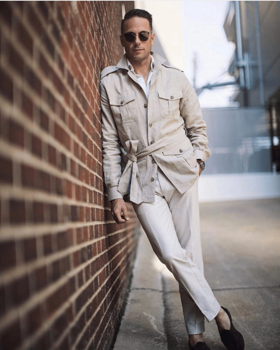 (product) Stone Solid Linen Safari Shirt Jacket, styled with white trousers and sunglasses against a brick wall - custom suits nyc bespoke tailor midtown, noho