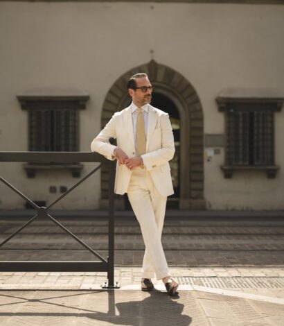 Brian wearing a cream linen suit with a white shirt and beige tie, styled with sunglasses and loafers