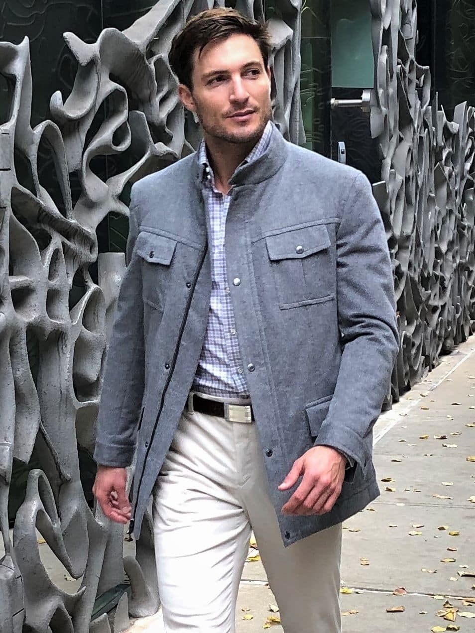 Bobby wearing a light grey field jacket with flap pockets, standing outdoors