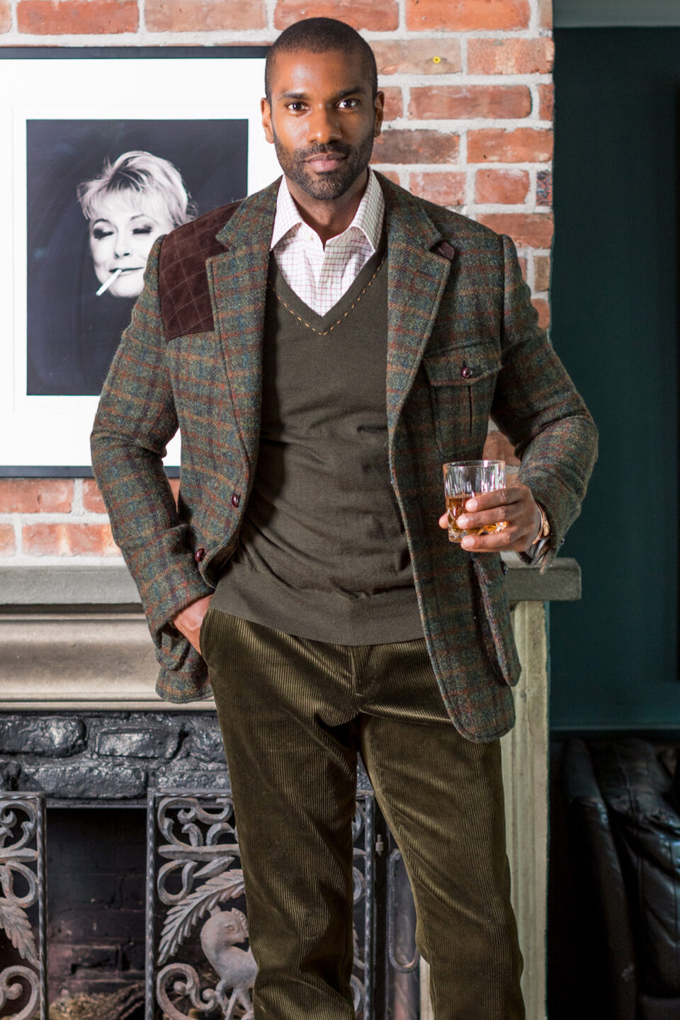 (product) Green With Multicoloured Overchecks Shooting Jacket, paired with a brown sweater and white shirt in a sophisticated indoor setting