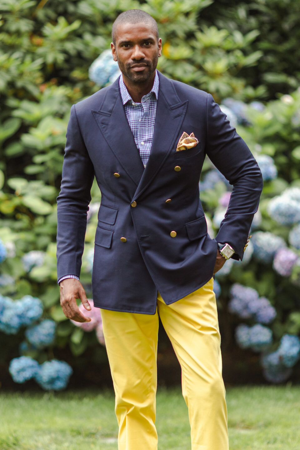 (product) Navy Solid Weave Nano 120S Sport Coat with gold buttons, paired with a navy shirt in a garden setting