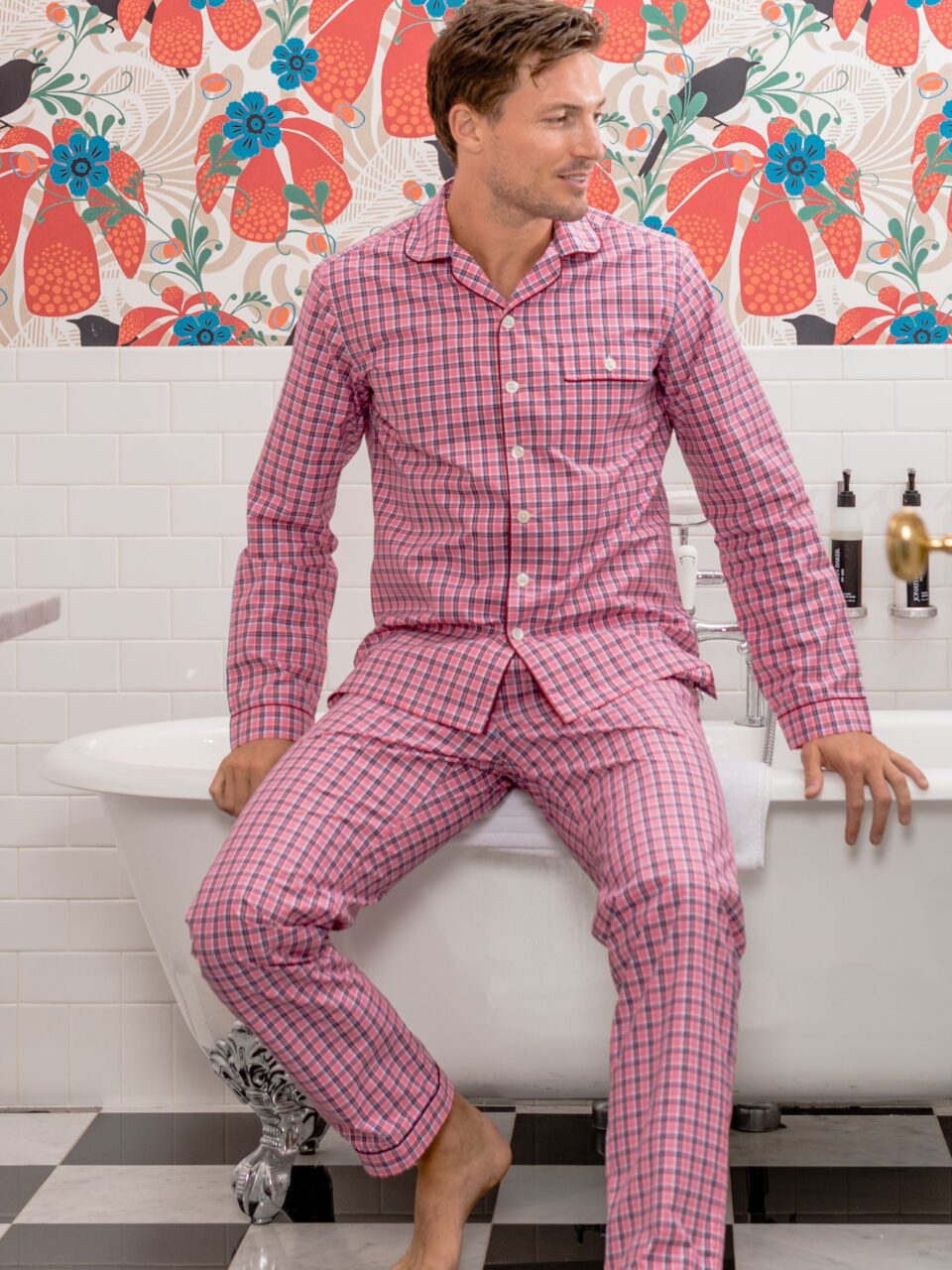 Relaxed-fit red and pink check pajamas worn by a model in a vibrant setting with floral wallpaper