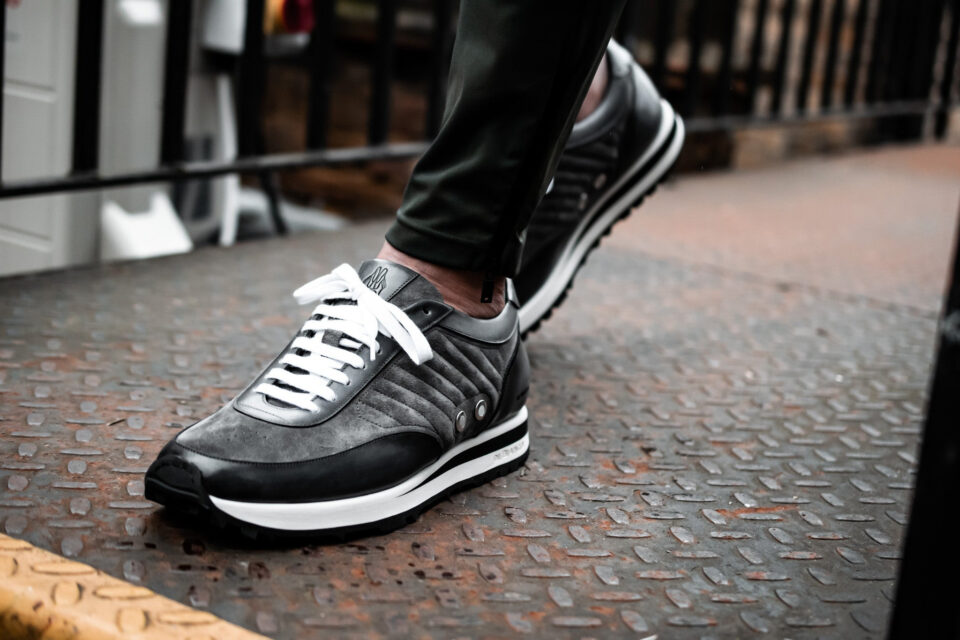 (product) Daytona Fumo Dress Sneaker, worn outdoors in a stylish setting