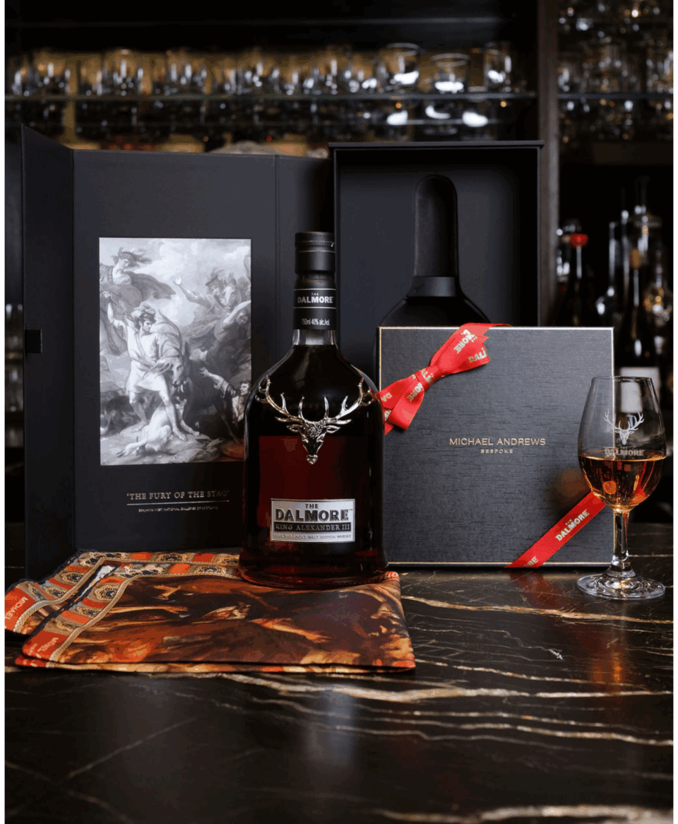 'The Fury of the Stag' Limited Edition Pocket Square displayed with Dalmore Whisky, a Michael Andrews Bespoke gift box, and a whisky glass on a black marble surface